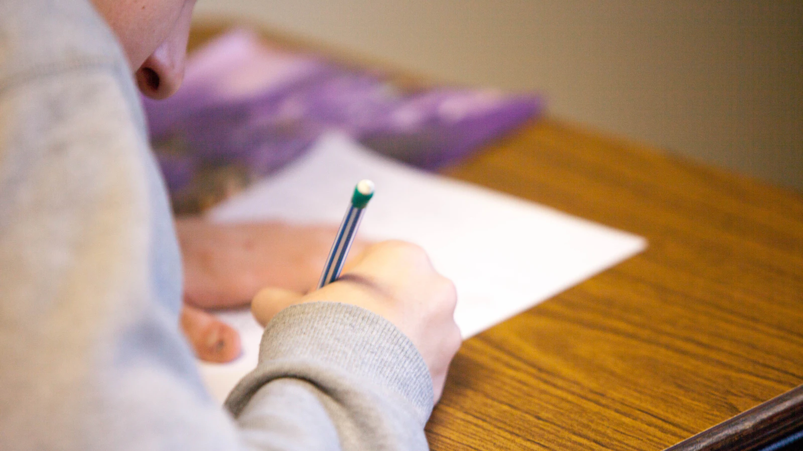 Una persona escribe con un lápiz sobre una hoja de papel en una mesa.
