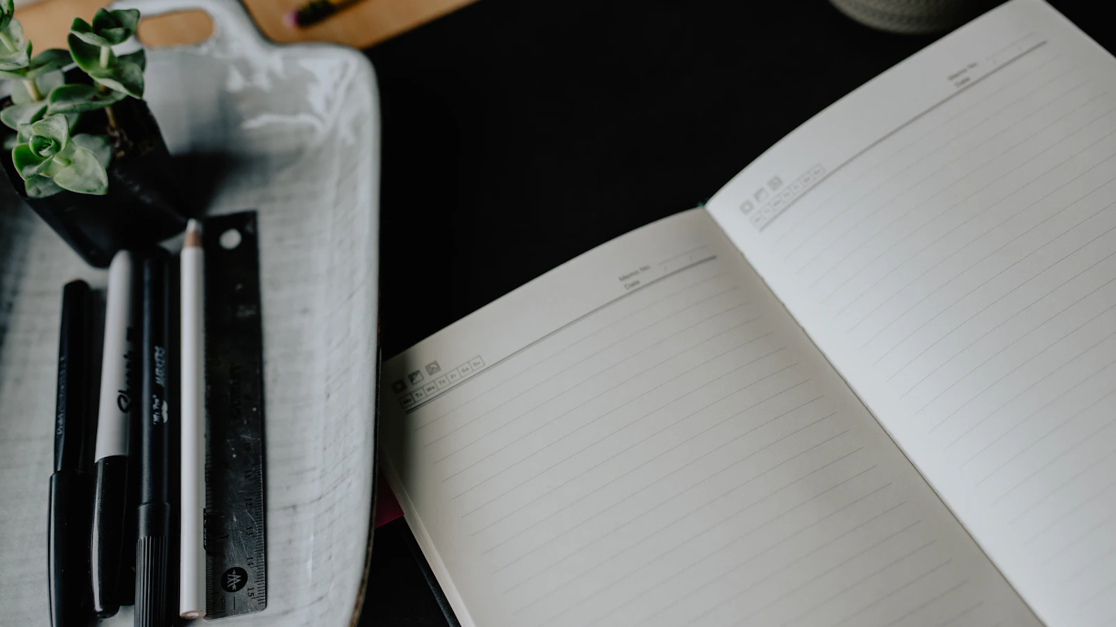 Cuaderno abierto y material de escritura sobre una mesa para organizar tareas y fechas.