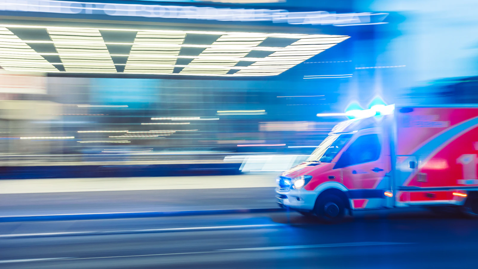 Ambulancia con luces azules circulando por una ciudad.